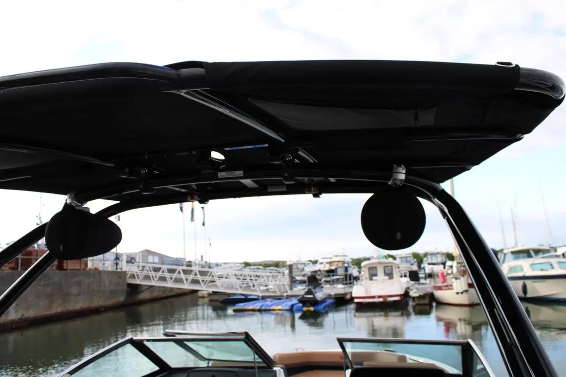 View from a boat canopy overlooking a marina, with various boats docked and a calm water surface reflecting the sky.